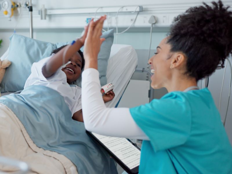 A female nurse and a child as a patient share a high five